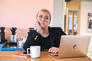 Woman at desk with laptop thinking